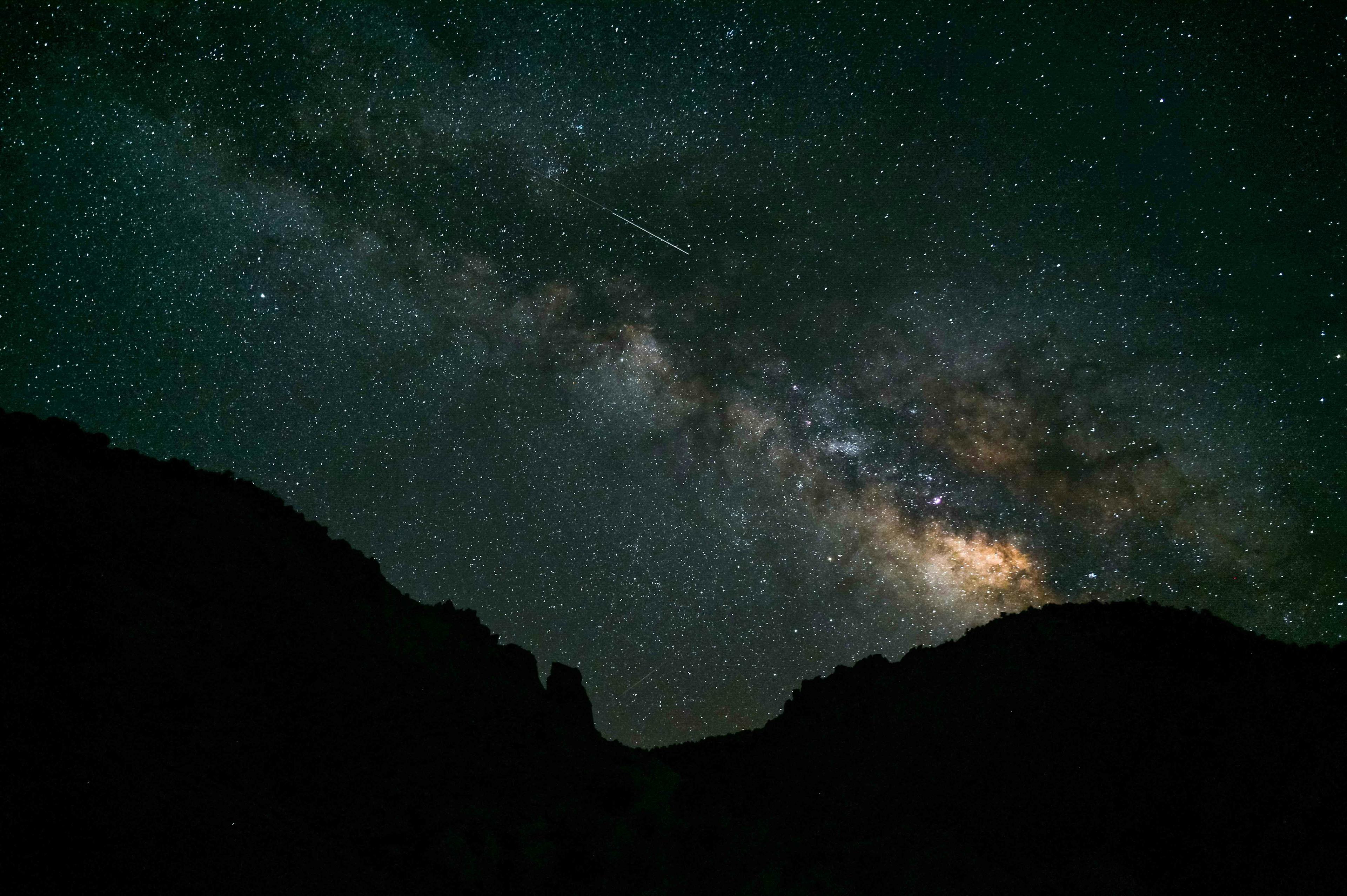The milky way stretches over some hills in Utah