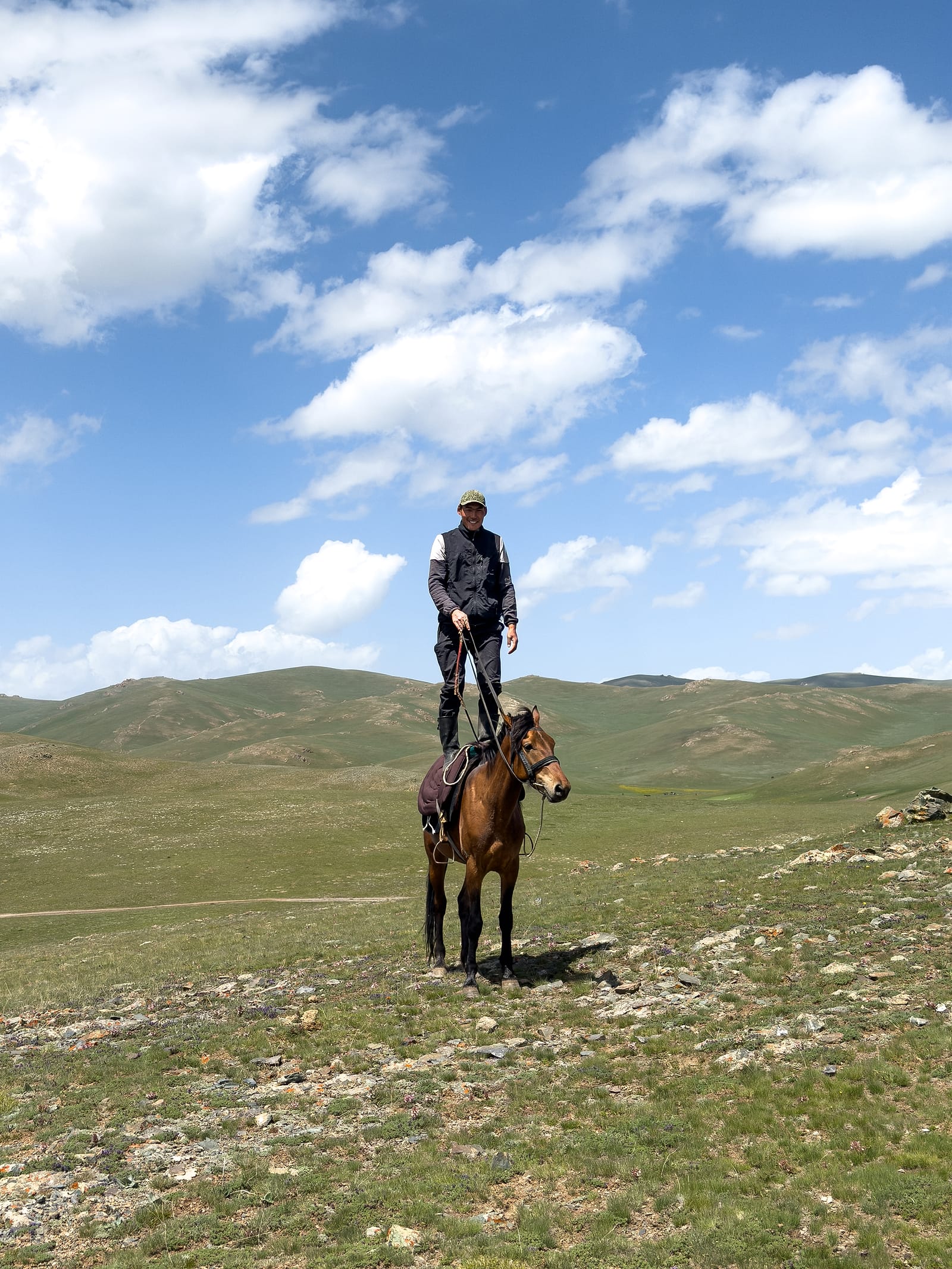 A herder standing on his horse's back